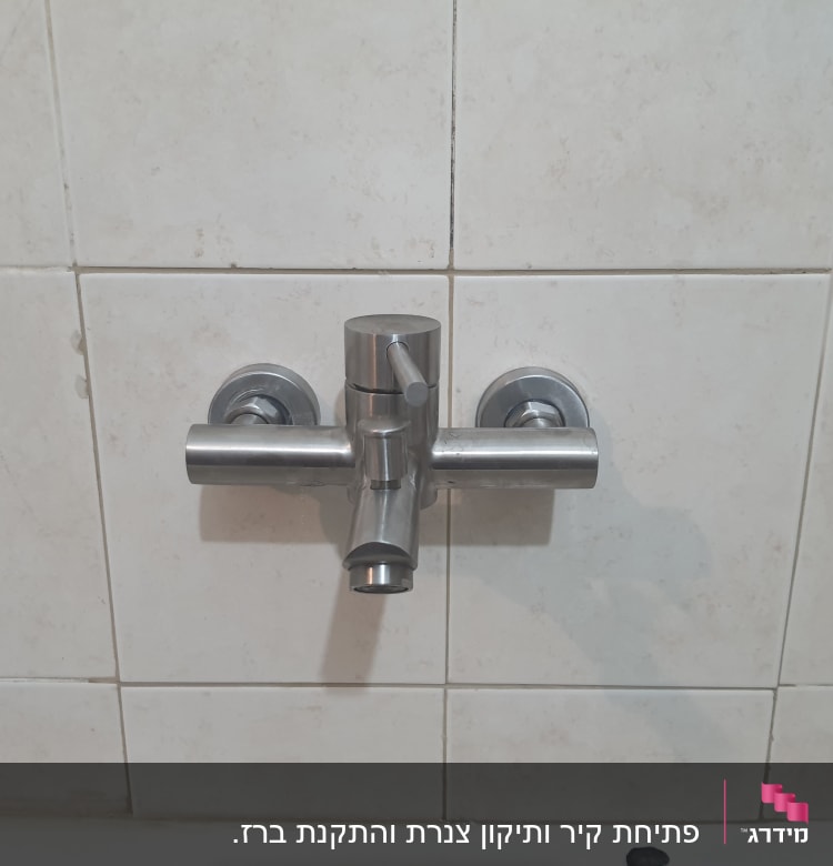 ברז מתכת מותקן על קיר אריחים לבנים